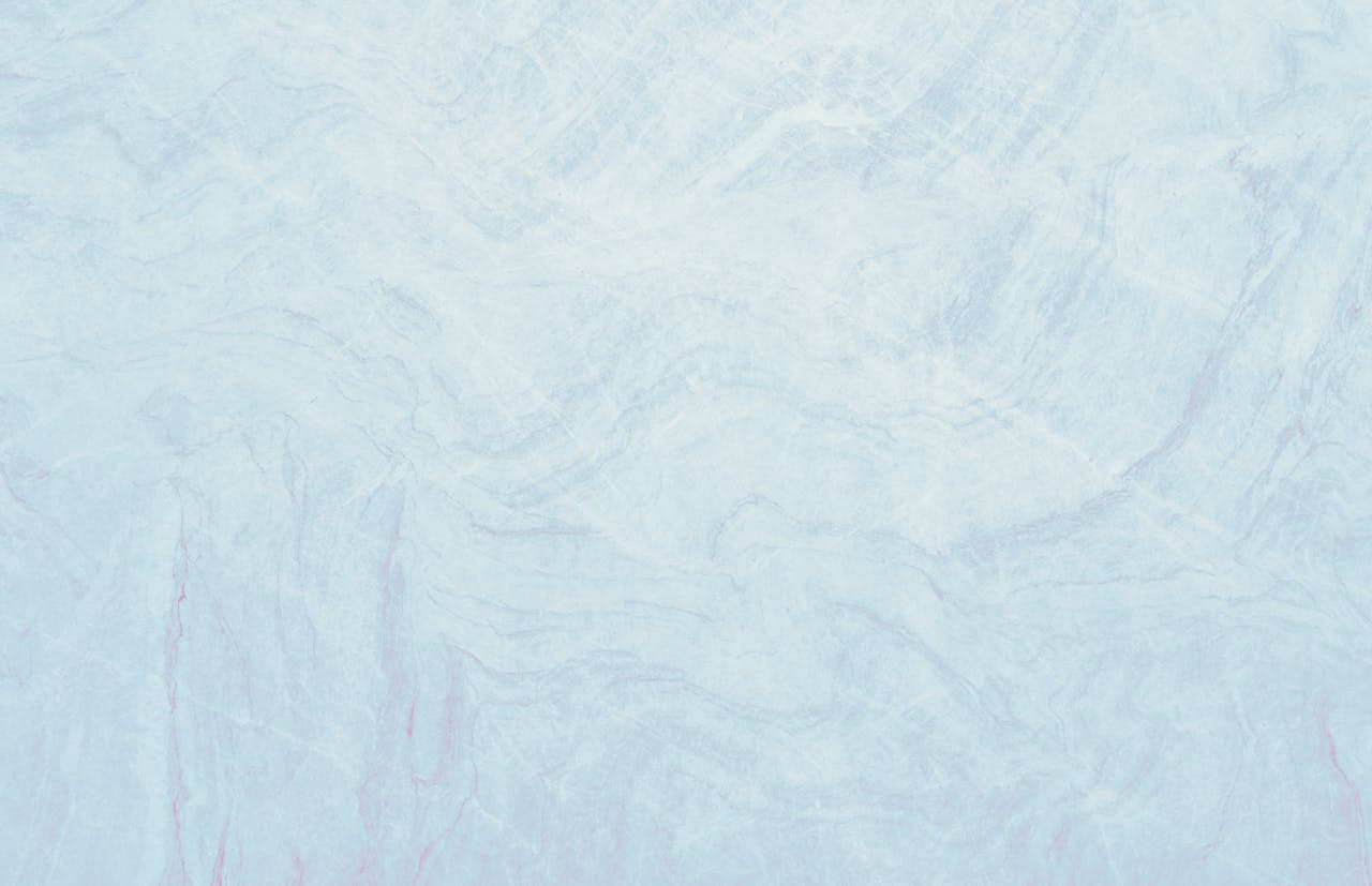 Light pastel blue marble texture showcasing smooth surface with soft wave patterns, ideal for design use.