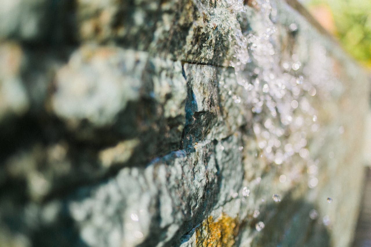 Detailed close-up of a textured rock surface with glistening water droplets.