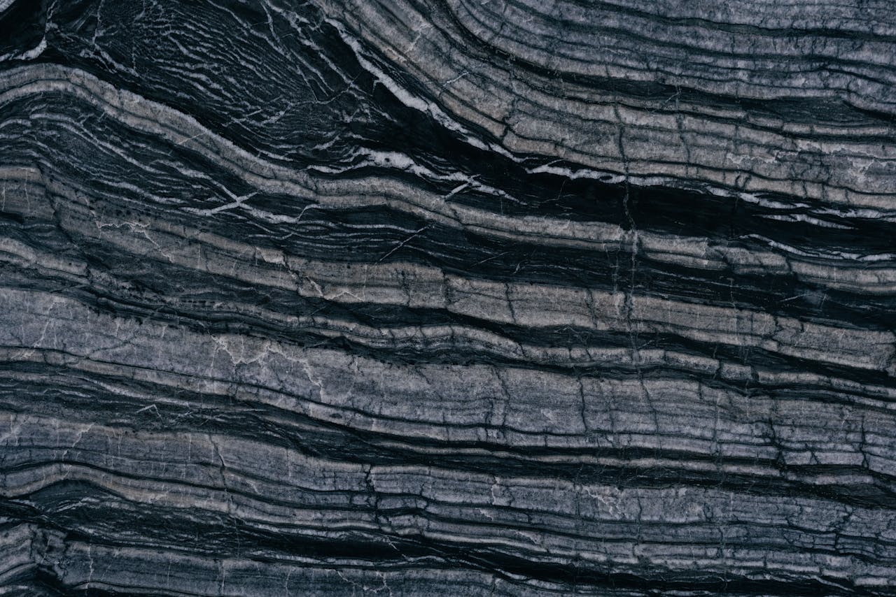Detailed texture of layered stone, showcasing natural patterns and dark tones.